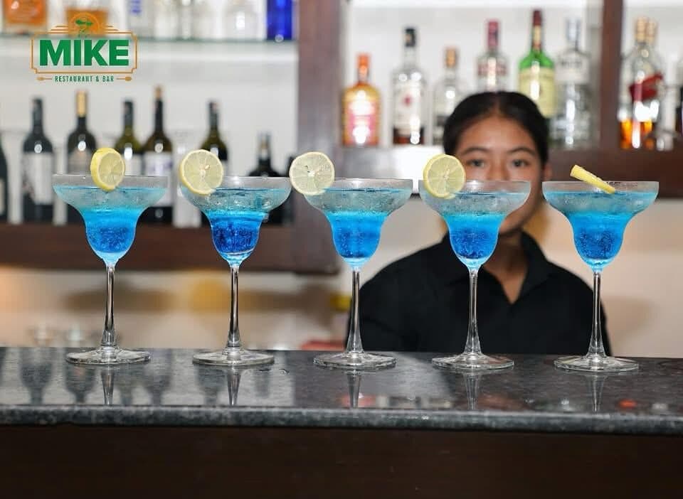Five blue cocktails lined up on the bar