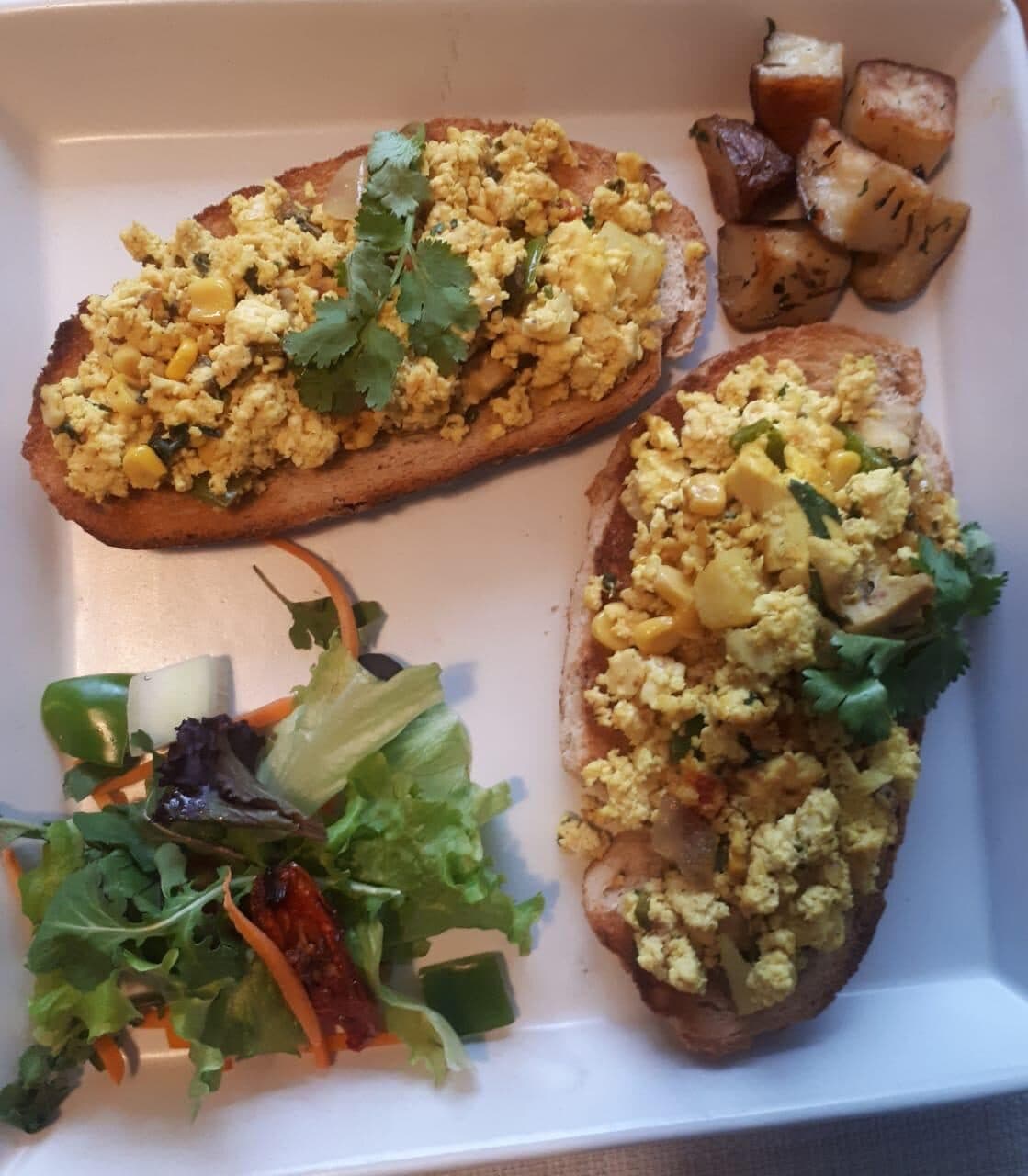 Scrambled eggs on toast with salad and potatoes