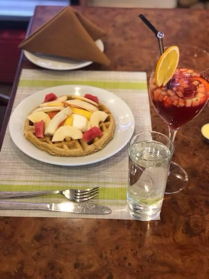 Waffle topped with fresh fruit beside a glass of sangria